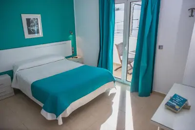 a bedroom with a bed with blue walls and a balcony at Hostal Victoria Mar in Chipiona