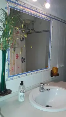 a bathroom sink with a mirror and a vase of flowers at Chalet la Huerta con piscina y wifi in Conil de la Frontera