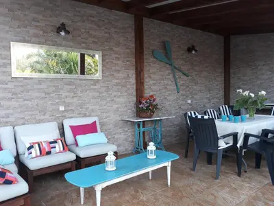 a patio with couches and tables and a table and chairs at Chalet la Huerta con piscina y wifi in Conil de la Frontera