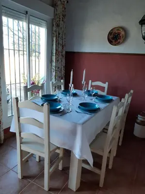 a dining room table with blue plates and chairs at Chalet la Huerta con piscina y wifi in Conil de la Frontera