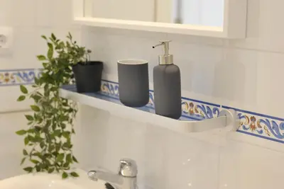 a bathroom sink with a soap dispenser on a shelf at Moderno Apartamento junto a la Playa in Sanlúcar de Barrameda