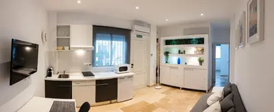 a kitchen with white cabinets and a couch in a room at Moderno Apartamento junto a la Playa in Sanlúcar de Barrameda