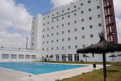 a hotel with a swimming pool in front of a building at Albergue Inturjoven Jerez De La Frontera in Jerez de la Frontera