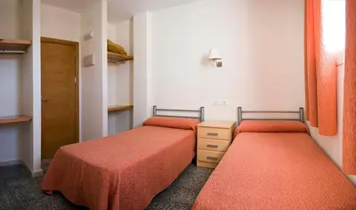 two beds in a small room with orange sheets at Albergue Inturjoven Jerez De La Frontera in Jerez de la Frontera