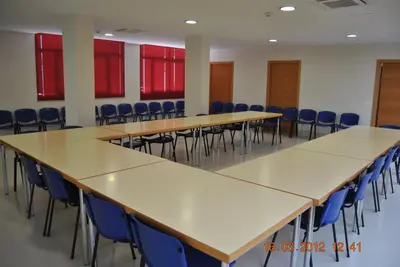 a row of tables and chairs in a room with red windows at Albergue Inturjoven Jerez De La Frontera in Jerez de la Frontera
