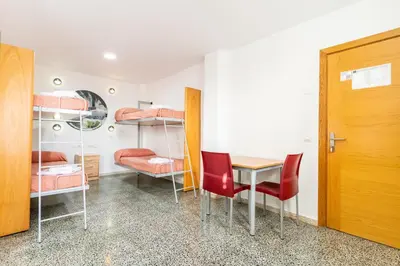 a room with a table and chairs and bunk beds at Albergue Inturjoven Jerez De La Frontera in Jerez de la Frontera
