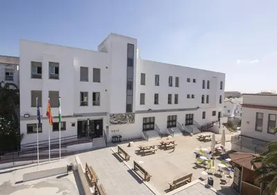 a large white building with benches in front of it at Albergue Inturjoven Chipiona in Chipiona