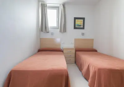 a bedroom with two beds with orange sheets at Albergue Inturjoven Chipiona in Chipiona