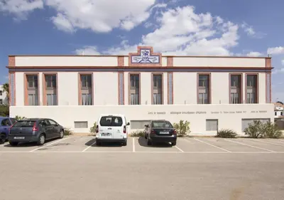 a building with cars parked in a parking lot at Albergue Inturjoven Chipiona in Chipiona