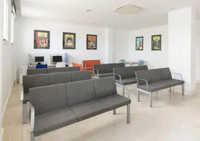 a waiting room with gray couches and chairs at Albergue Inturjoven Chipiona in Chipiona