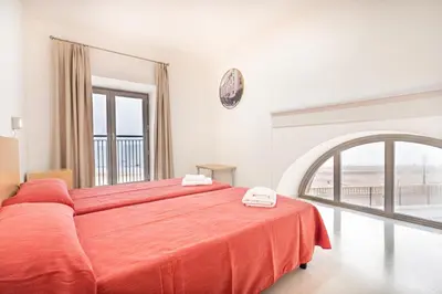 a bedroom with a large bed with an orange blanket at Albergue Inturjoven Chipiona in Chipiona
