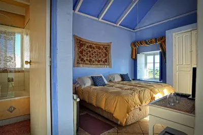 a blue bedroom with a bed and a tub at La Casa de Bovedas Charming Inn in Arcos de la Frontera