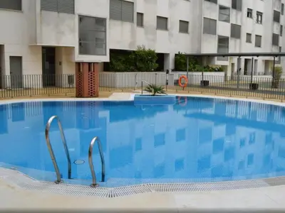a large blue swimming pool in front of a building at estudio santa maria in El Puerto de Santa María