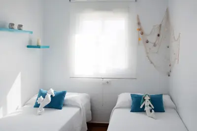 two beds in a room with blue pillows at Summerland Apartments Rota in Rota
