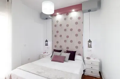 a bedroom with a white bed with pink pillows at Summerland Apartments Rota in Rota