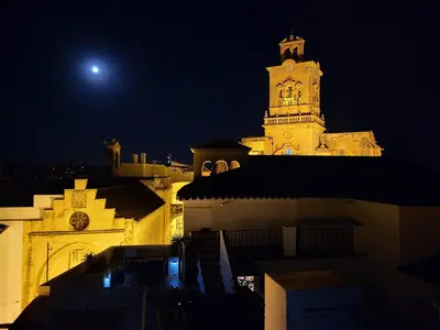 a large building with a clock tower at night at Casa Campana in Arcos de la Frontera