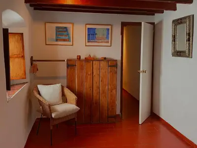 a hallway with a chair and a wooden cabinet at Casa Campana in Arcos de la Frontera
