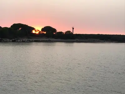 a sunset over a body of water with a lighthouse at Ático con Encanto in Sanlúcar de Barrameda