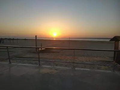 a sunset on the beach with the sun setting at Ático con Encanto in Sanlúcar de Barrameda