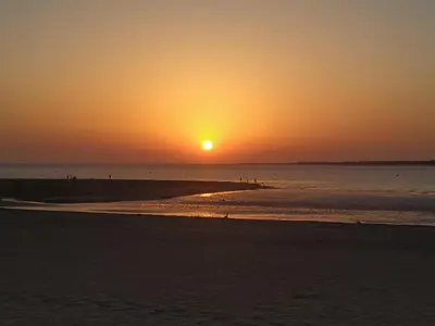 a sunset on a beach with the sun setting at Ático con Encanto in Sanlúcar de Barrameda