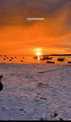 a sunset on a beach with boats in the water at Ático con Encanto in Sanlúcar de Barrameda
