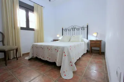 a bedroom with a bed with a white blanket and a window at Villa Rocío-Conil in Conil de la Frontera