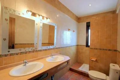 a bathroom with two sinks and a toilet and a mirror at Villa Rocío-Conil in Conil de la Frontera