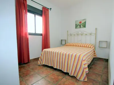a bedroom with a bed and red curtains and a window at Villa Rocío-Conil in Conil de la Frontera