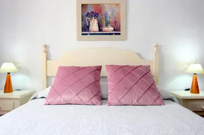 a bedroom with a bed with two pink pillows at Villa Rocío-Conil in Conil de la Frontera