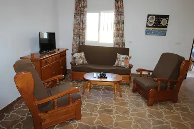 a living room with a couch and chairs and a tv at Casa Melli in Conil de la Frontera