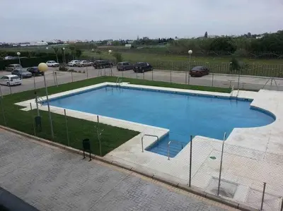 a large swimming pool in a parking lot at Enjoy Life Chipiona in Chipiona