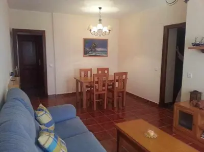 a living room with a blue couch and a table and chairs at Enjoy Life Chipiona in Chipiona