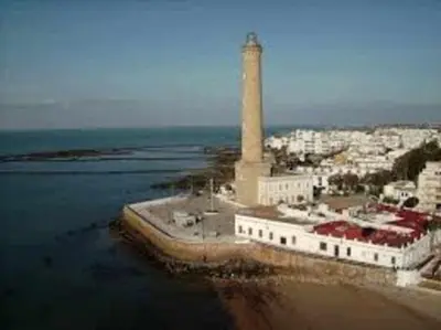 a lighthouse in a city next to the water at Enjoy Life Chipiona in Chipiona