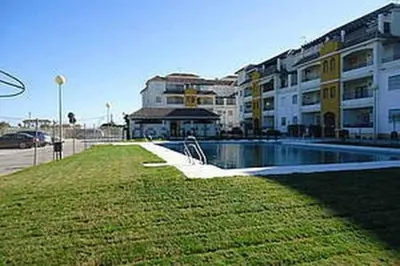 a building with a swimming pool in front of a building at Enjoy Life Chipiona in Chipiona