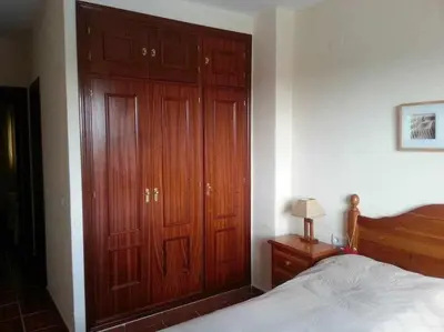a bedroom with a large wooden closet and a bed at Enjoy Life Chipiona in Chipiona
