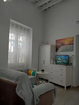 a living room with a bed and a dresser with a tv at La Caleta de Cadiz WiFi in Cádiz