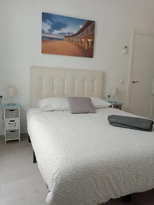 a bedroom with a white bed with a picture on the wall at La Caleta de Cadiz WiFi in Cádiz