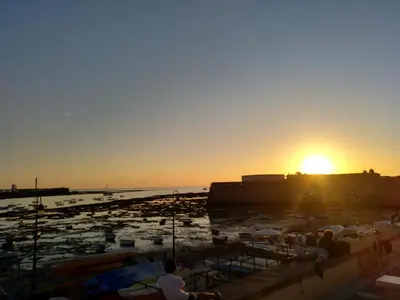 a sunset over a harbor with boats in the water at La Caleta de Cadiz WiFi in Cádiz