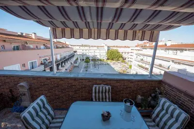 a table and chairs on a balcony with an umbrella at Ático Las Infantas- Parking gratuito in Sanlúcar de Barrameda