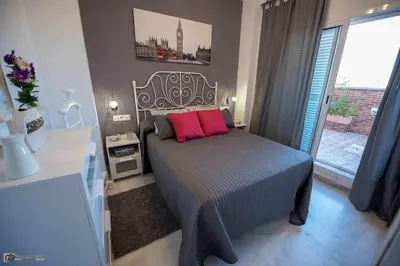 a bedroom with a bed with pink pillows and a window at Ático Las Infantas- Parking gratuito in Sanlúcar de Barrameda
