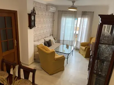 a living room with a couch and chairs and a clock at Ático Las Infantas- Parking gratuito in Sanlúcar de Barrameda