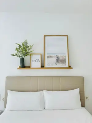 a bed with two pictures on a shelf above it at LUMINOSO APARTAMENTO en el centro de Cádiz in Cádiz