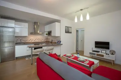 a living room with a red couch and a kitchen at LUMINOSO APARTAMENTO en el centro de Cádiz in Cádiz