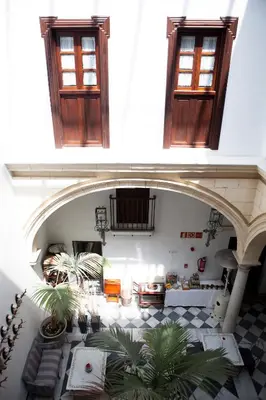 an archway in a building with windows and plants at Hostal Palacio San Bartolomé in El Puerto de Santa María