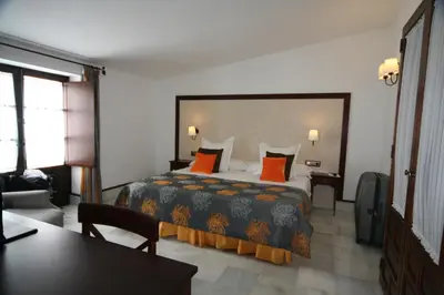a bedroom with a large bed with orange pillows at Hostal Palacio San Bartolomé in El Puerto de Santa María