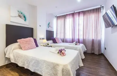 a room with two beds and a window at Brisas Playa 3 Baños in Cádiz