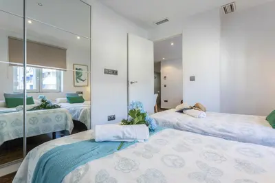 a bedroom with two beds and a mirror at Brisas Playa 3 Baños in Cádiz