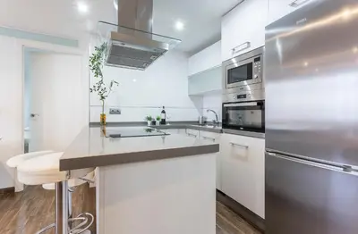 a white kitchen with a sink and a refrigerator at Brisas Playa 3 Baños in Cádiz
