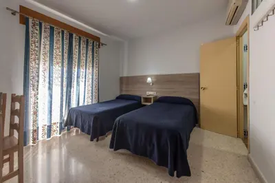 a room with two beds and a window at Hotel San Andres in Jerez de la Frontera