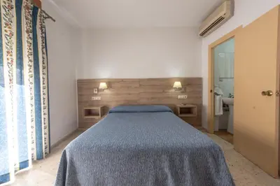 a bedroom with a bed with a blue blanket at Hotel San Andres in Jerez de la Frontera